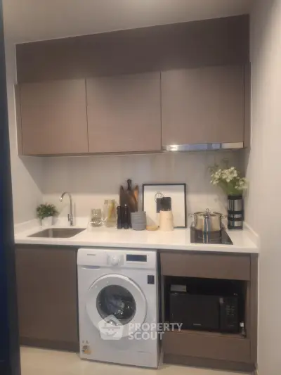 Modern kitchen with washing machine and sleek cabinetry in compact design
