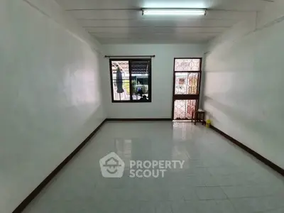 Spacious empty room with tiled floor and window view, ideal for customization.