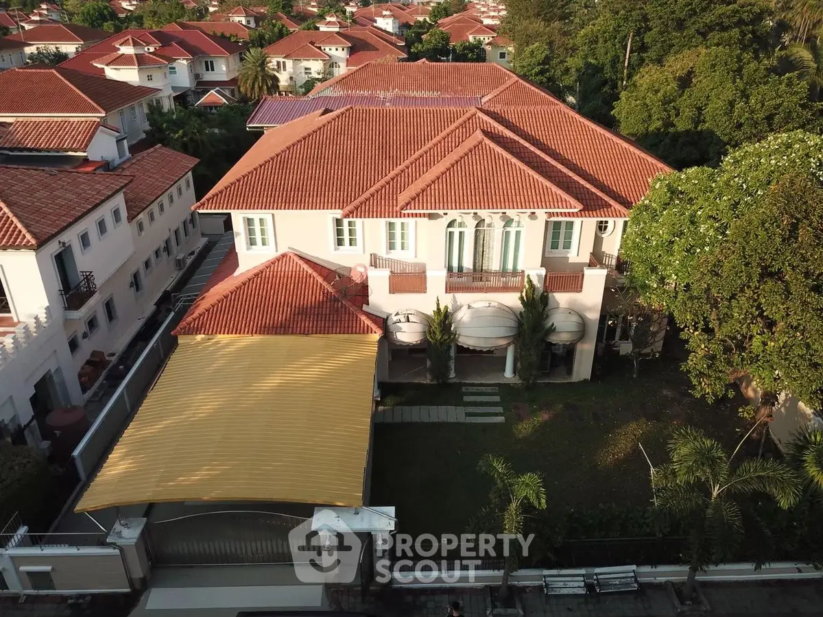 Luxurious villa with red-tiled roof and spacious garden in a serene neighborhood.