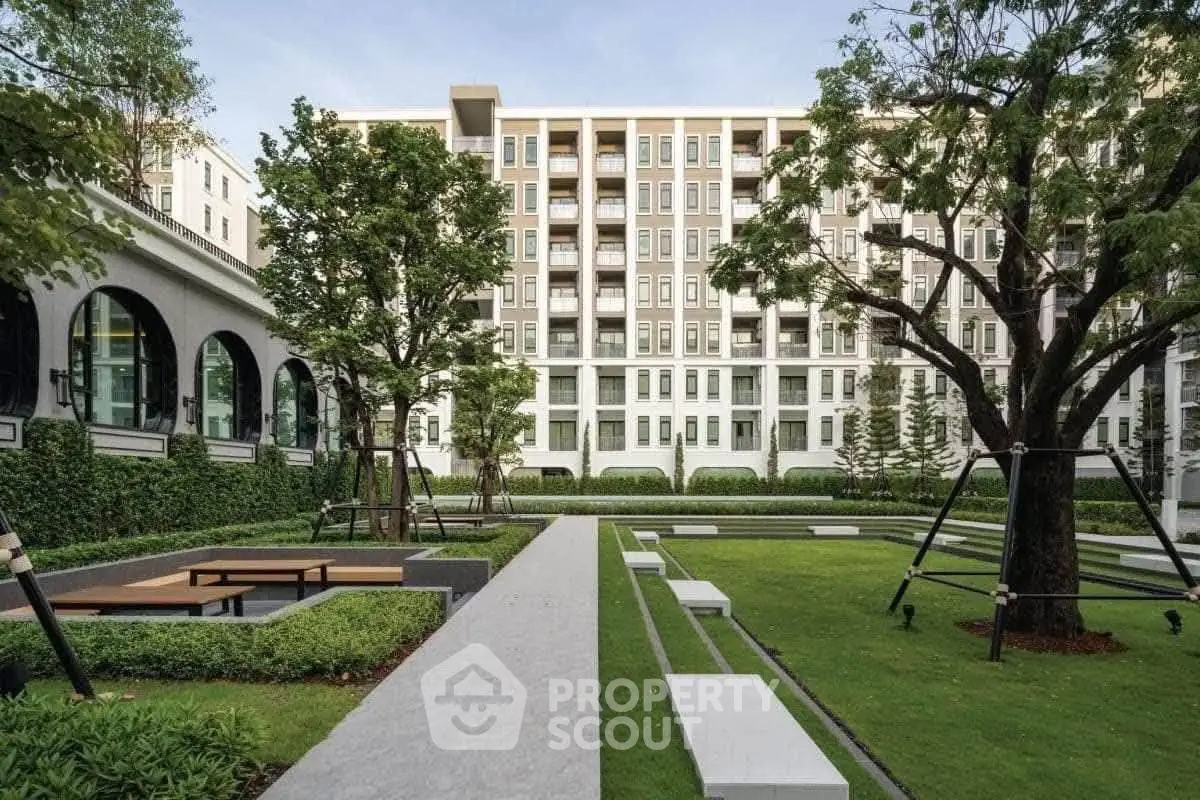 Modern apartment building with lush garden and outdoor seating area, perfect for relaxation.