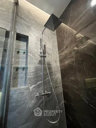 Luxurious modern bathroom with sleek rainfall shower and elegant marble tiles.