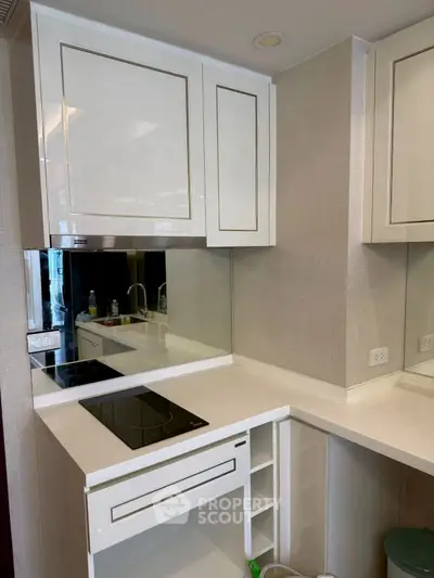 Modern kitchen with sleek white cabinets and electric cooktop