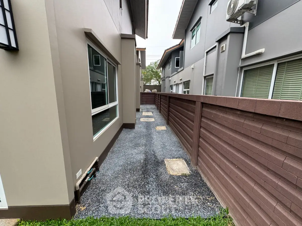 Modern residential exterior with gravel pathway and wooden fence.