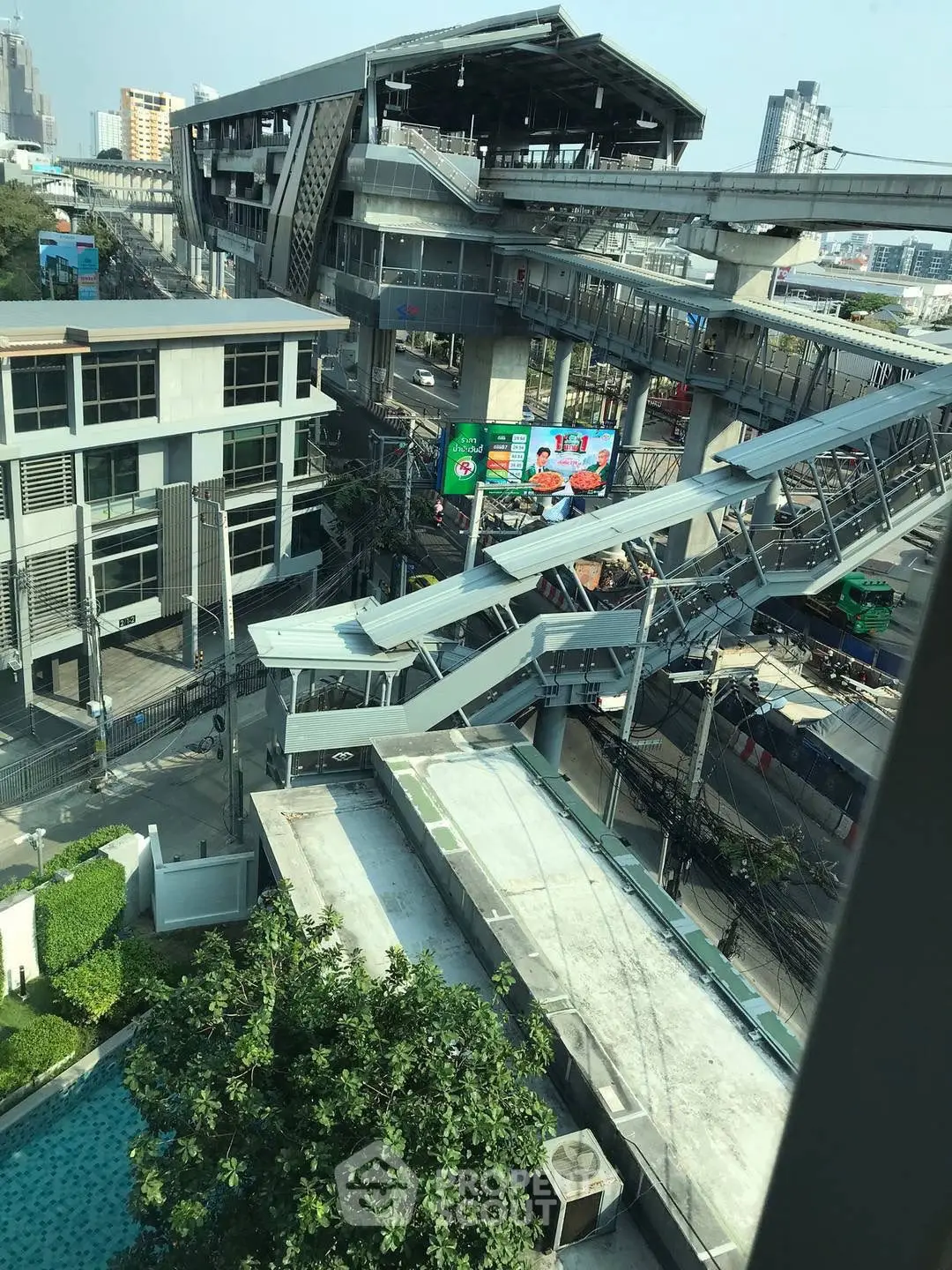 Urban view of modern building and elevated train station with cityscape backdrop.