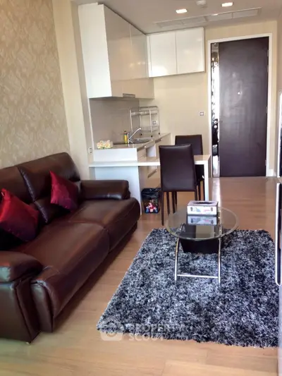 Modern living room with sleek kitchen, leather sofa, and stylish decor in open layout apartment.