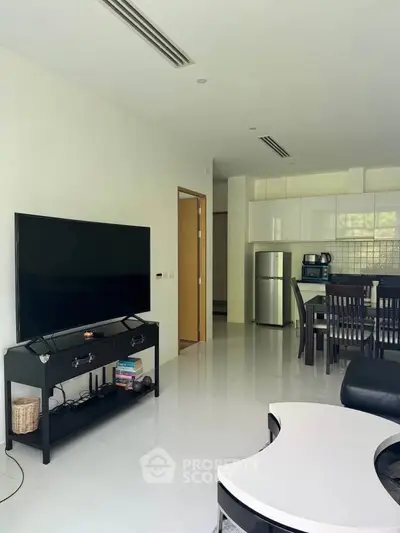 Modern open-plan living room with sleek kitchen and large TV, perfect for entertaining.