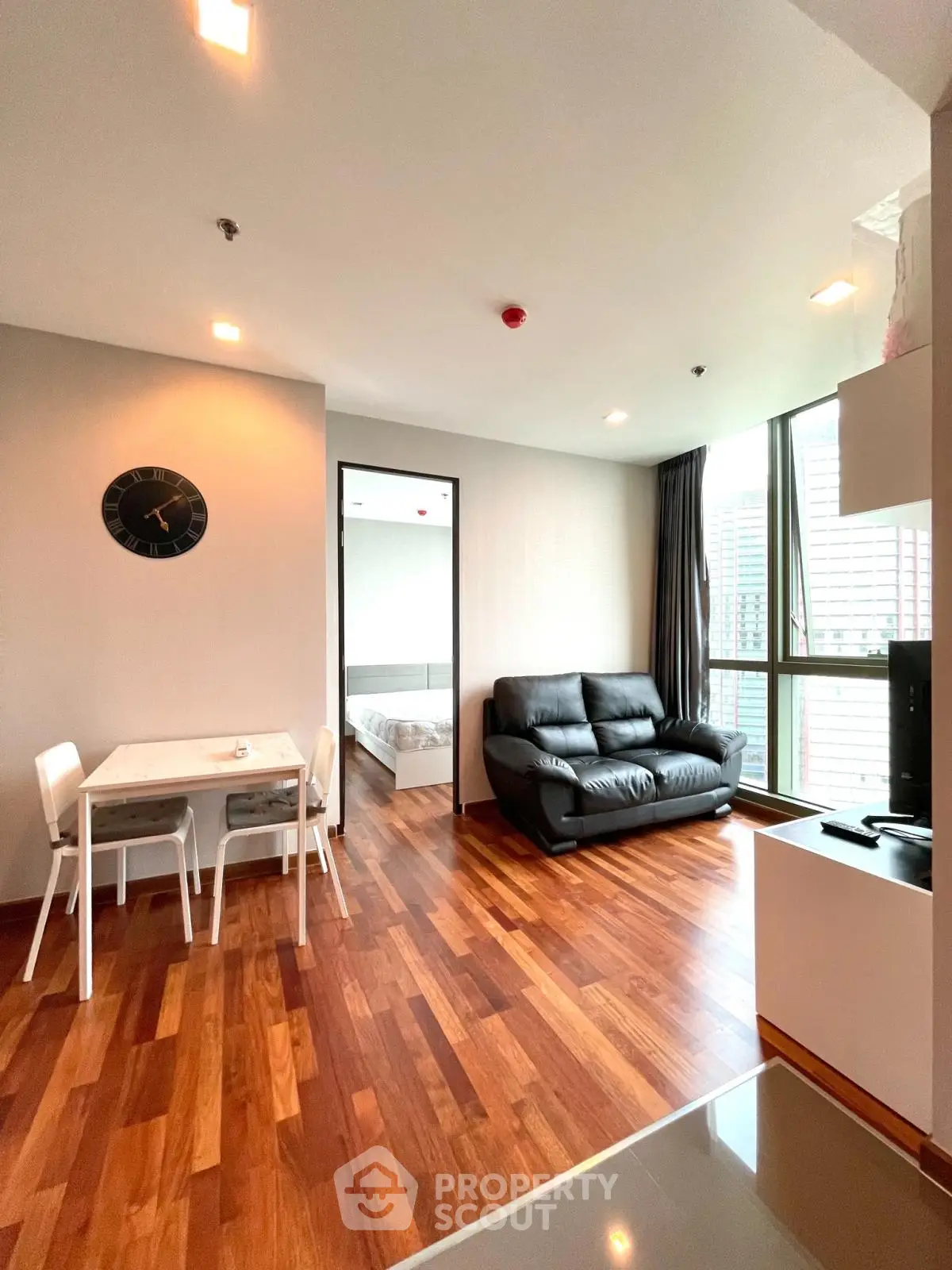 Modern living room with hardwood floors, cozy sofa, and dining area in open layout apartment.