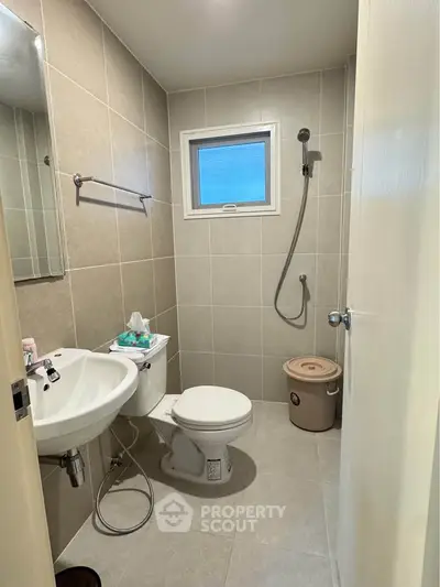 Modern bathroom with shower, toilet, and sink in neutral tones.