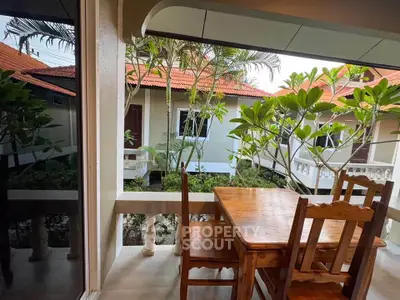 Charming balcony view with wooden dining set and lush greenery in a serene residential setting.