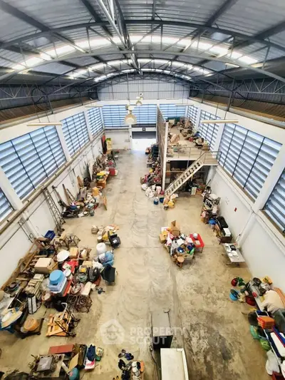 Spacious industrial warehouse with high ceilings and mezzanine storage area.