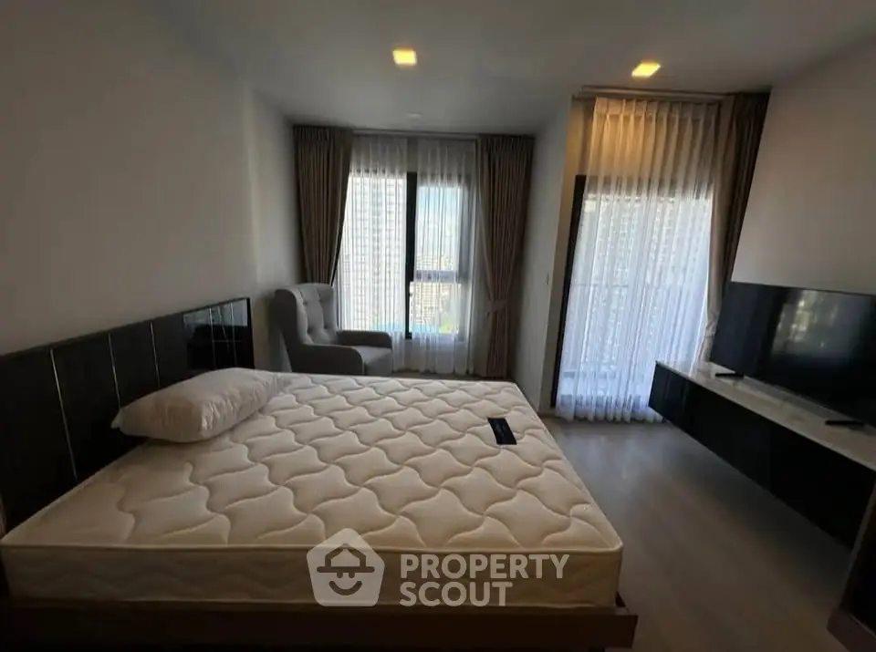 Spacious bedroom with modern decor and large windows offering natural light.