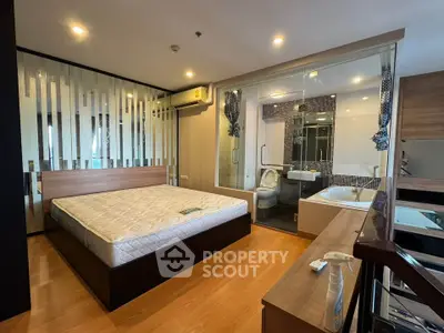 Modern bedroom with glass wall bathroom and wooden flooring in luxury apartment