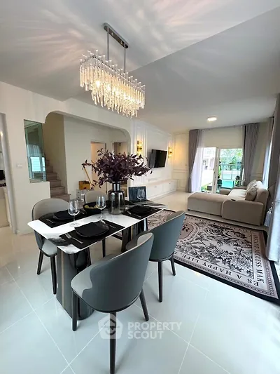 Luxurious open-plan living and dining area with elegant chandelier and modern decor.