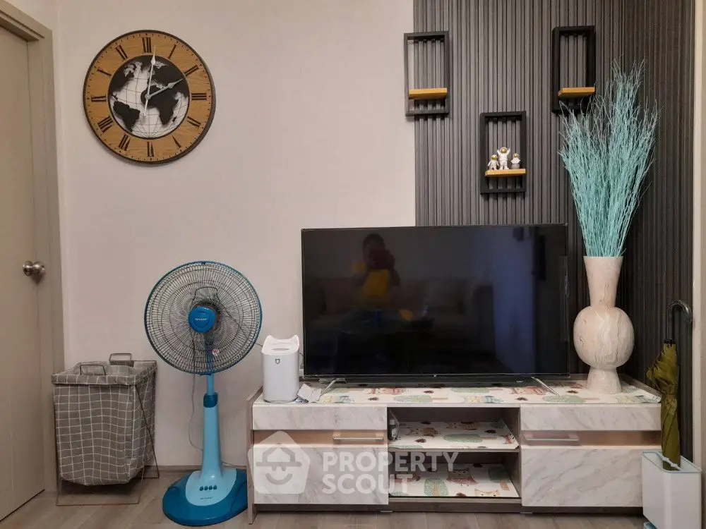 Modern living room with stylish decor, featuring a large TV, elegant clock, and decorative shelves.