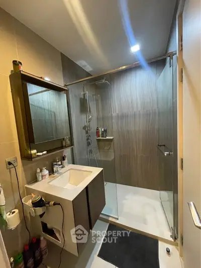Modern bathroom with glass shower and sleek vanity in contemporary apartment.