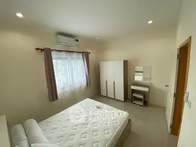 Spacious bedroom with modern furnishings and natural light, featuring a comfortable bed and ample storage.