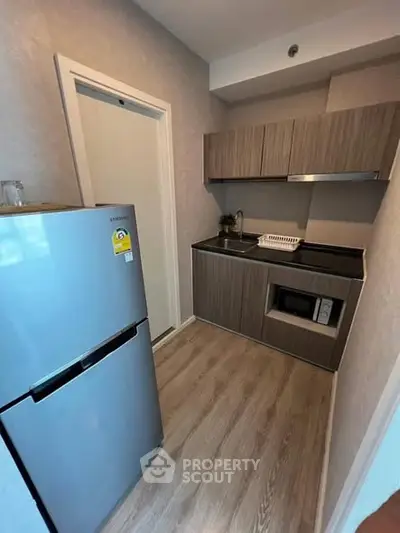 Modern compact kitchen with sleek cabinetry and stainless steel fridge