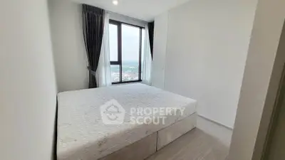 Spacious bedroom with large window offering stunning city views, perfect for relaxation and comfort.