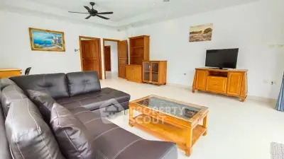Spacious living room with modern black leather sofa and wooden furniture