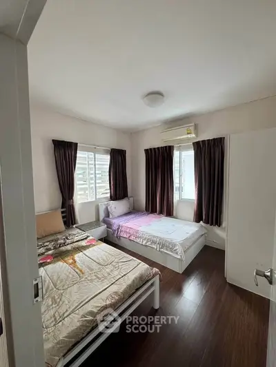 Spacious bedroom with two beds, large windows, and elegant curtains in a modern apartment.