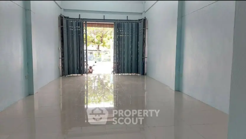 Spacious empty room with glossy tiled floor and large window view.