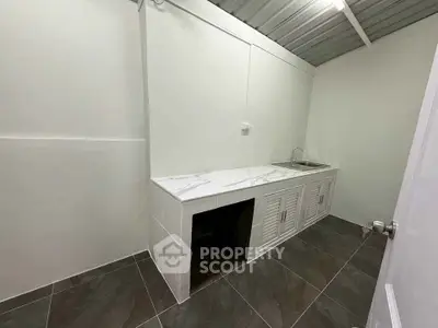 Minimalist kitchen with marble countertop and stainless steel sink in modern home.