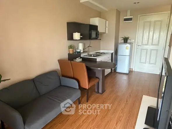 Cozy open-layout living room with compact kitchen and modern furnishings