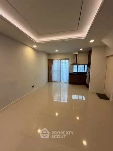 Spacious modern living room with sleek lighting and open kitchen layout.