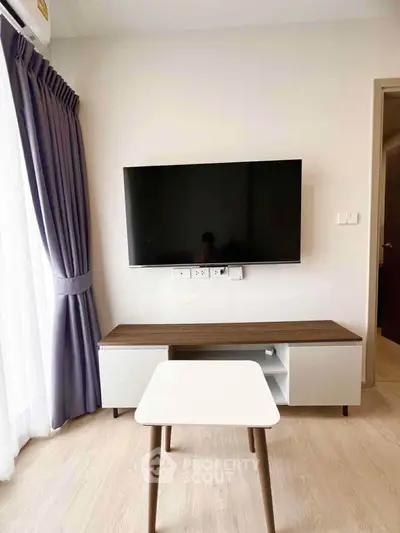 Modern living room with wall-mounted TV and stylish furniture in a bright apartment.