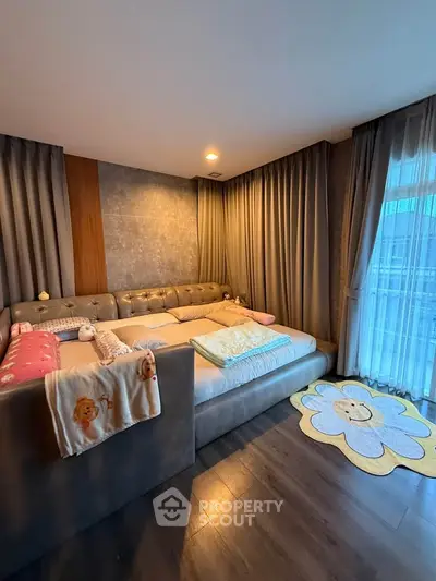 Cozy bedroom with plush bed and floor-to-ceiling curtains, featuring a charming flower rug.