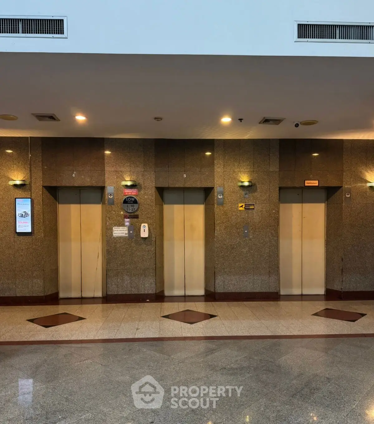 Modern building lobby with three elevators and polished granite walls.