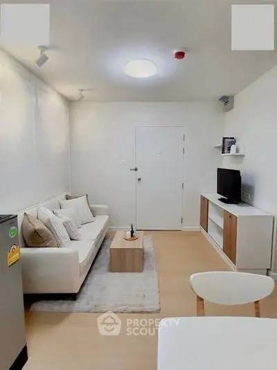 Modern living room with cozy sofa, sleek TV stand, and minimalist decor in a bright, compact space.