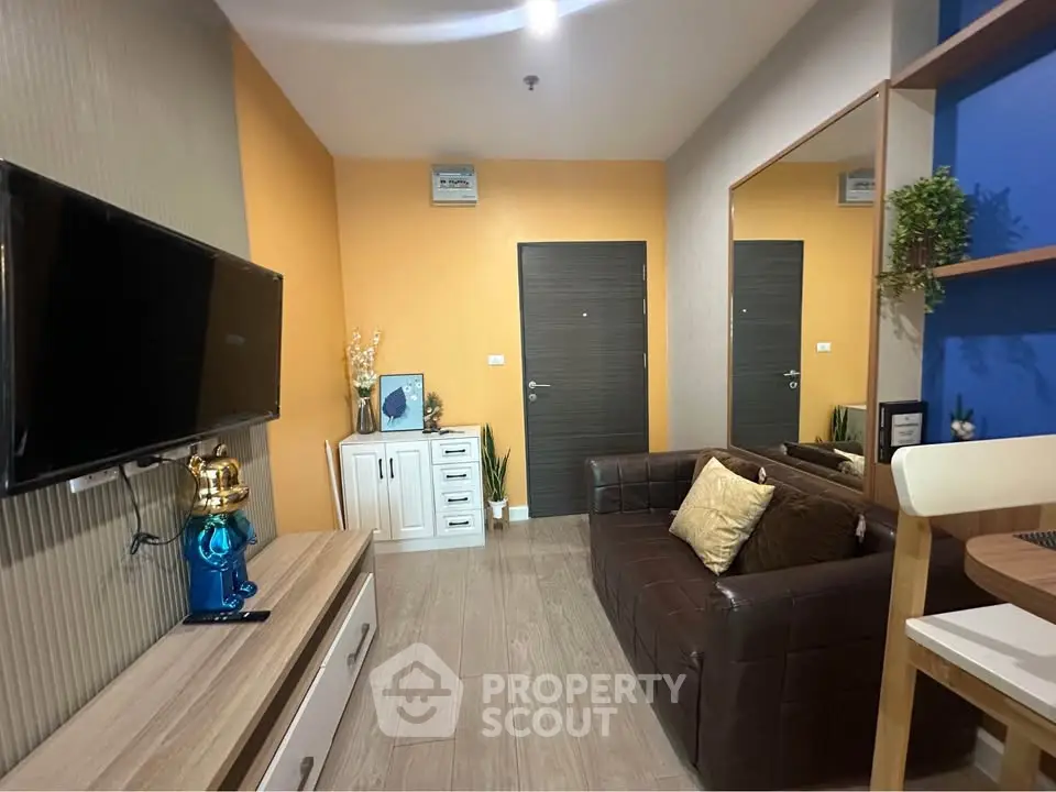 Modern living room with stylish decor and wall-mounted TV in cozy apartment.