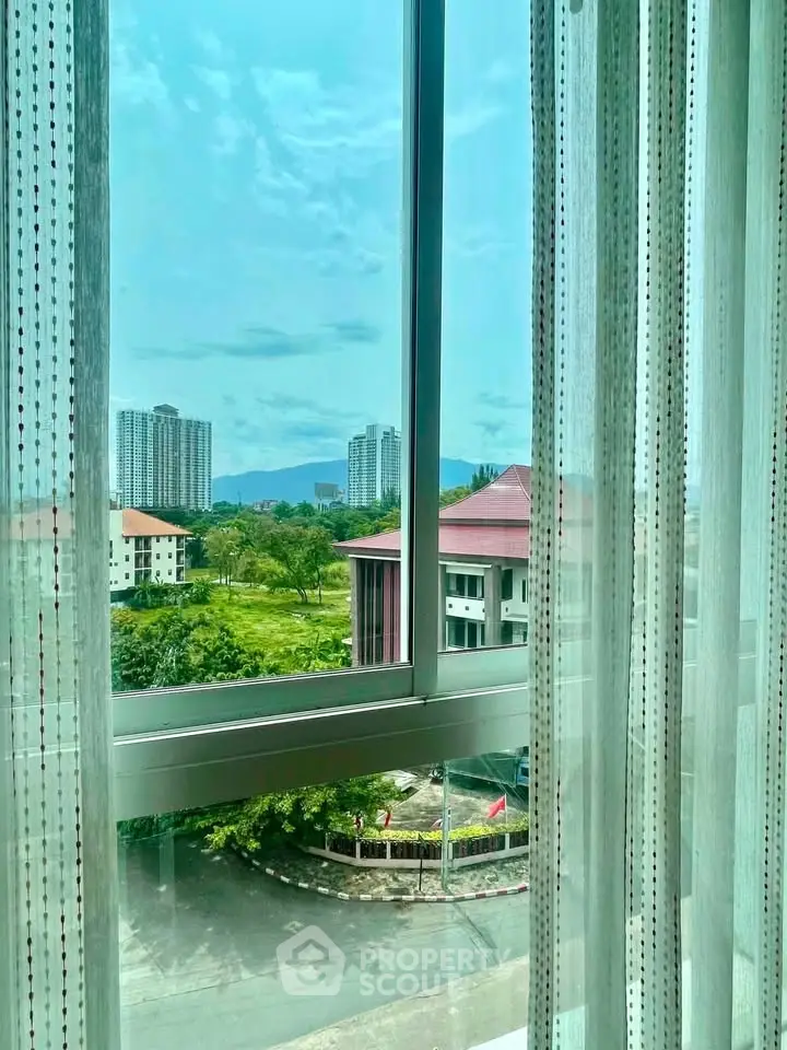 Stunning cityscape view from a modern apartment window with lush greenery and high-rise buildings.