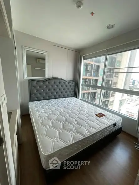 Spacious bedroom with large window offering city views and elegant decor.