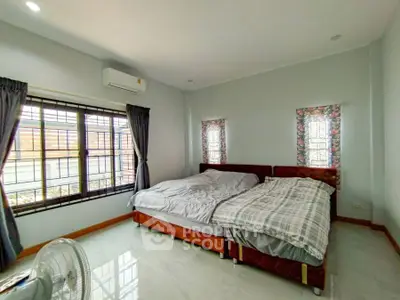 Spacious bedroom with large windows and twin beds, featuring modern decor and natural light.