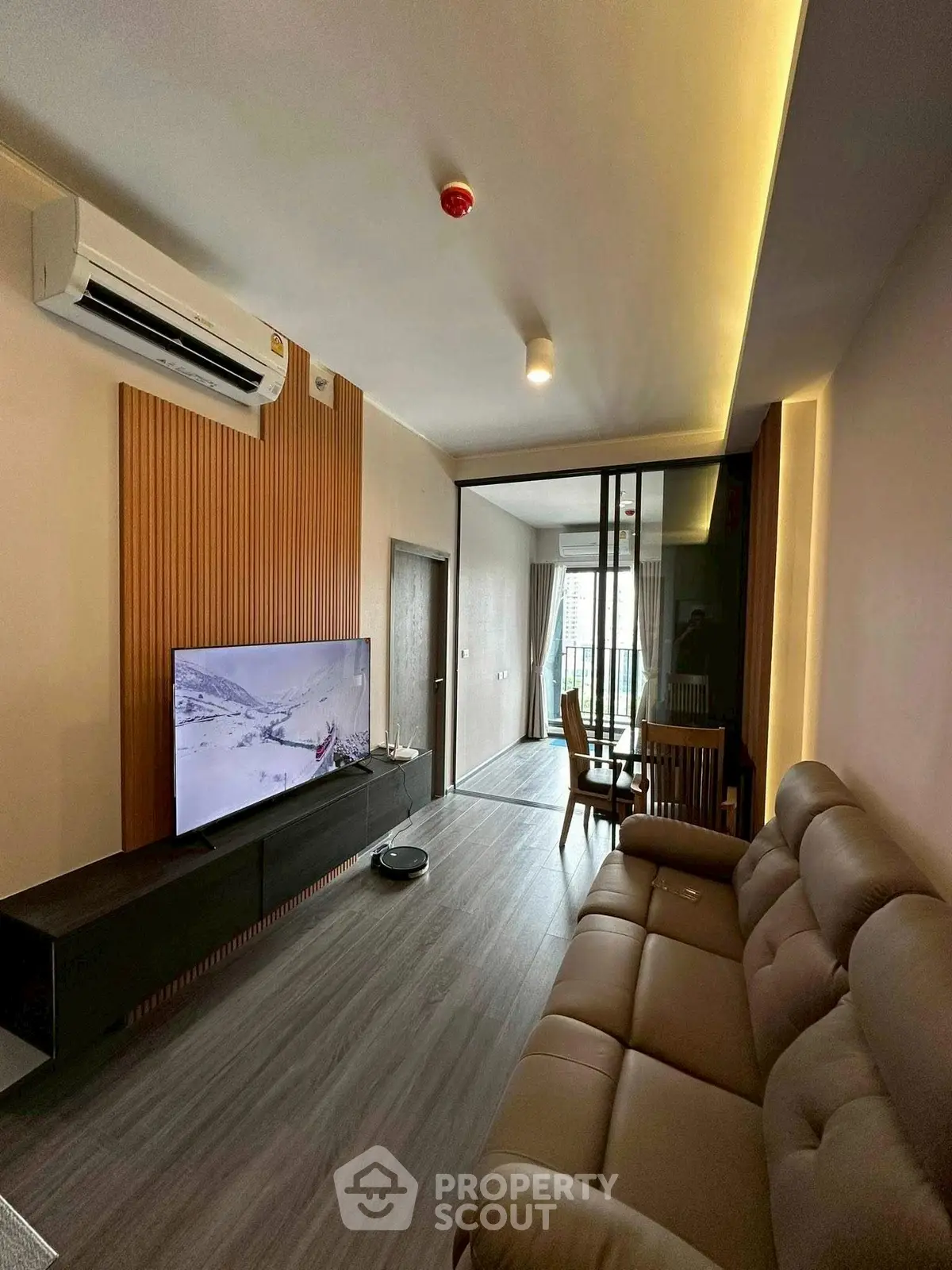 Modern living room with sleek design and spacious layout, featuring a large TV and comfortable seating.