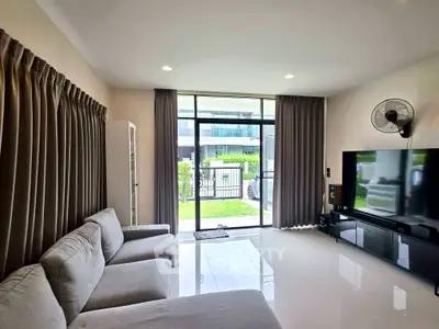 Spacious living room with modern decor and large windows overlooking a garden, perfect for relaxation.