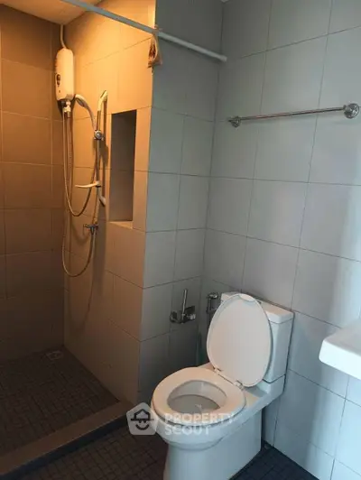 Modern bathroom with shower and toilet in sleek tiled design.