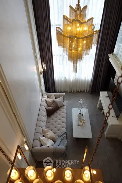 Luxurious living room with high ceiling, elegant chandelier, and plush sofa for sophisticated comfort.
