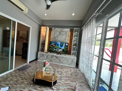 Spacious living room with modern decor and large windows offering natural light and outdoor views.