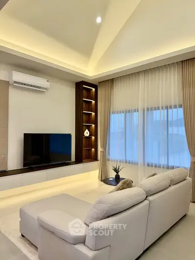 Elegant living room with modern decor, featuring a cozy sectional sofa, large TV, and ambient lighting.