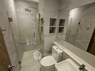 Modern bathroom with glass shower and sleek fixtures in contemporary apartment.