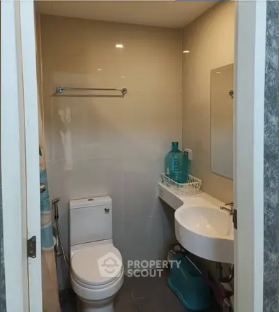 Modern bathroom with sleek fixtures and compact design, featuring a wall-mounted sink and toilet.