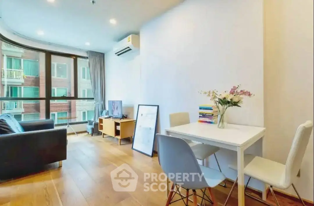 Modern living room with wooden floors, large windows, and stylish furniture.