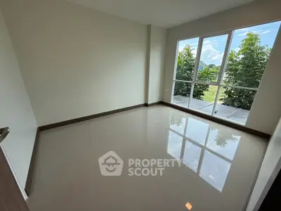 Spacious empty room with large windows offering lush green views, perfect for customization.