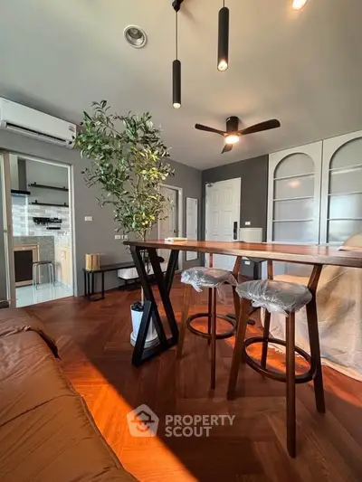 Modern living room with stylish furniture and open kitchen layout, featuring elegant wooden flooring and contemporary lighting.