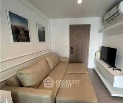 Modern living room with beige sofa, wall art, and mounted TV in a stylish apartment.