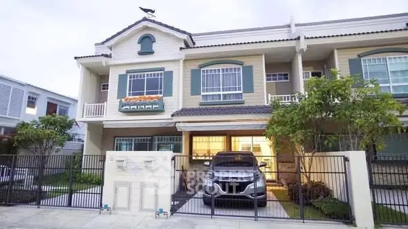 Charming two-story house with gated driveway and lush greenery