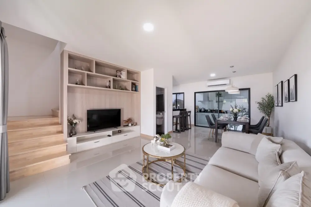 Spacious modern living room seamlessly connects to an outdoor balcony, featuring elegant furnishings and a chic neutral color palette.